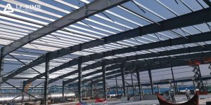 Portal frame steel structure industrial warehouse under construction Large-span portal frame steel structure industrial warehouse under construction, showing steel columns, roof purlins and skylights inside a power plant support building