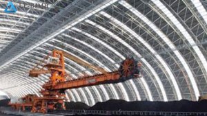 Interior of a barrel arch space frame storage shed with a stacker-reclaimer and coal stockpile.