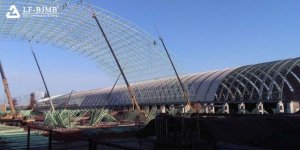 Large span bolted ball-joint space frame coal storage shed under construction, with cranes installing roof structure